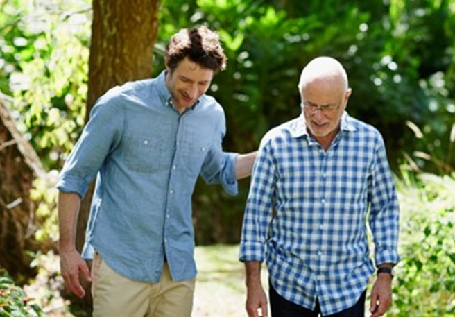 Sohn unterhält sich mit an IgAN erkrankten Vater beim Spaziergang im Wald  Sohn unterhält sich mit an IgAN erkrankten Vater beim Spaziergang im Wald